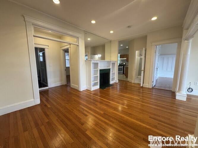 A spacious room with wood flooring and a fireplace.