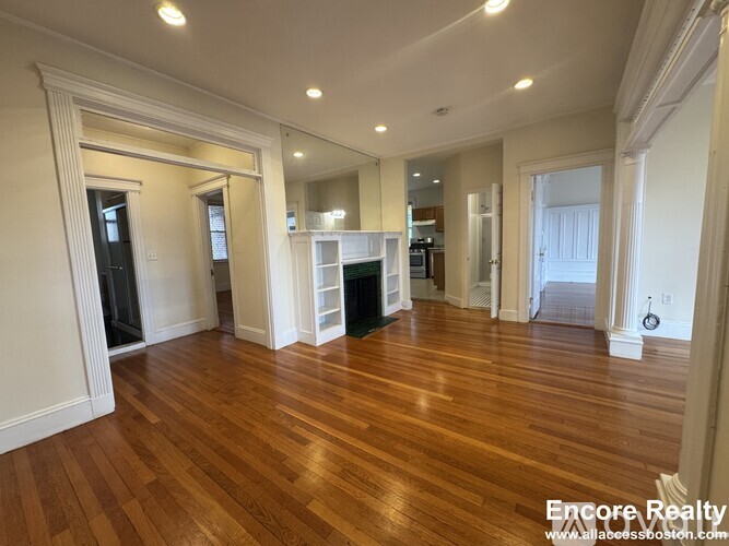 A spacious room with wooden floors and white walls.