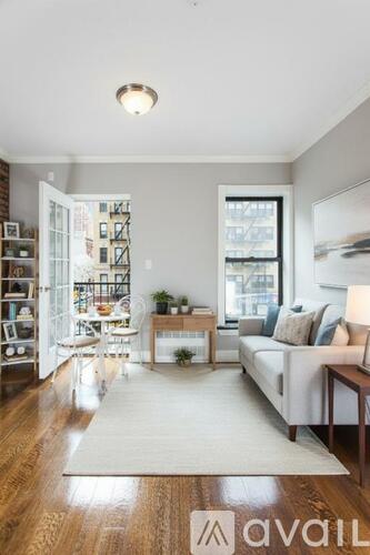 A living room with a white couch and a rug in the middle.