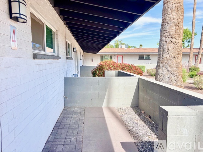 A long concrete walkway leads to a building with a red door.