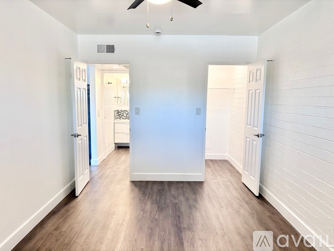 A spacious room with a ceiling fan and light, and a doorway leading to another room.