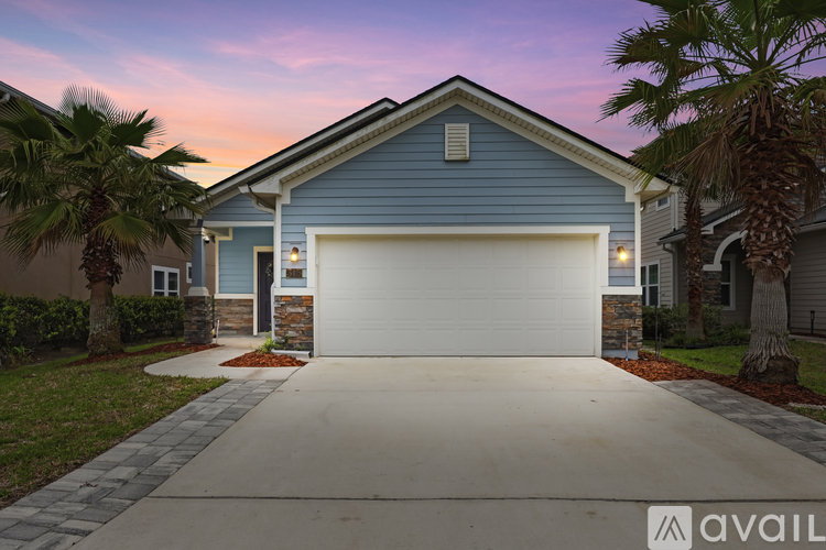 A house with a garage and palm trees in front.