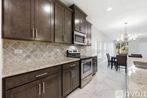 A kitchen with brown cabinets and a tile backsplash.