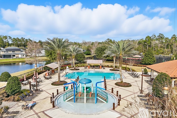 A large outdoor pool surrounded by palm trees and a deck.