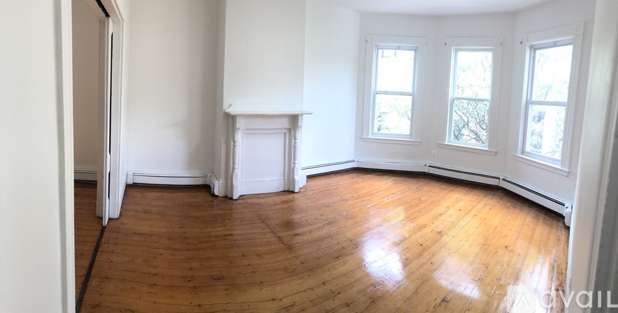 A room with wooden floors and three windows.