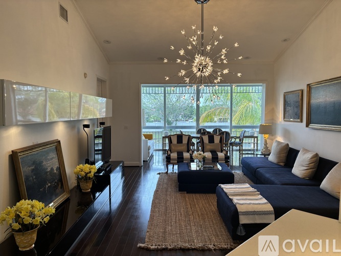 A living room with a dark blue couch and a chandelier hanging from the ceiling.