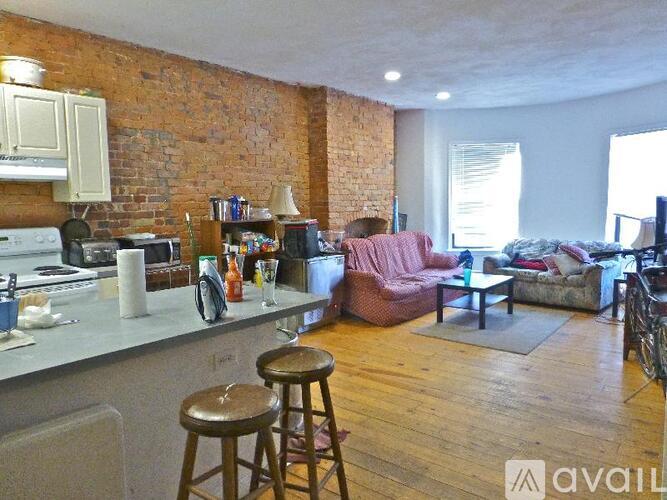 A kitchen with a brick wall and wooden floors.