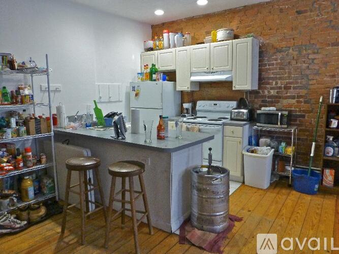 A kitchen with a brick wall and wooden floors.