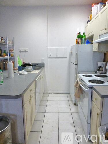 A kitchen with white appliances and white tiled floors.
