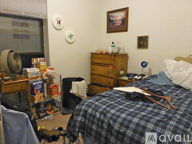 A bedroom with a bed, dresser, and a window with blinds.