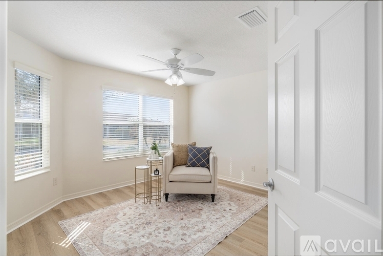 A living room with a beige couch and a ceiling fan.