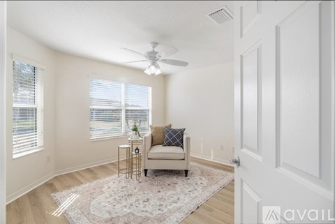 A living room with a beige couch and a ceiling fan.