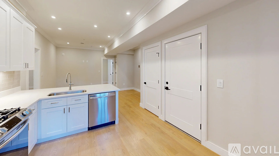 A modern kitchen with white cabinets and a wooden floor.
