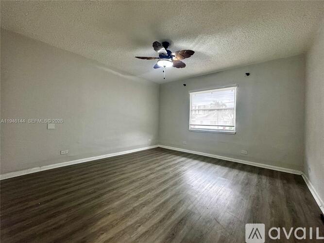 A room with a ceiling fan and wooden flooring.