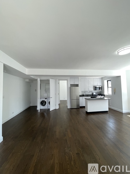 A spacious room with wooden floors and white walls.