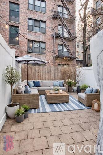 A patio with a couch, chairs, and a table with a plant on it.