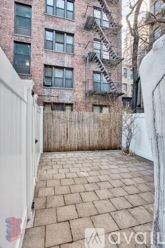 A brick building with a fire escape and a white fence.