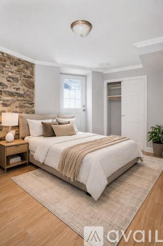 A bedroom with a large bed and a stone wall.