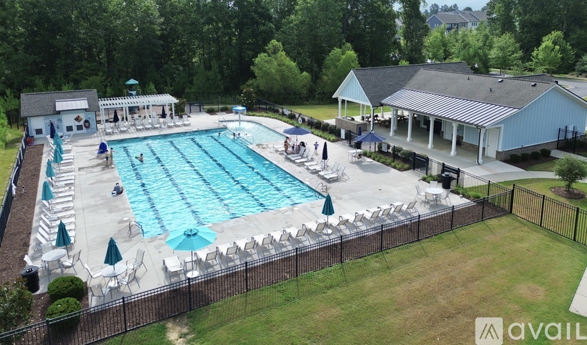An outdoor swimming pool surrounded by a fence and chairs.