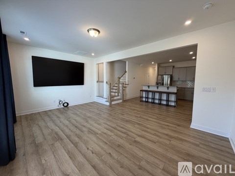 A spacious living room with a television and hardwood flooring.