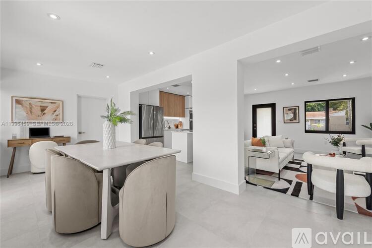 A modern living room with a white dining table and chairs.