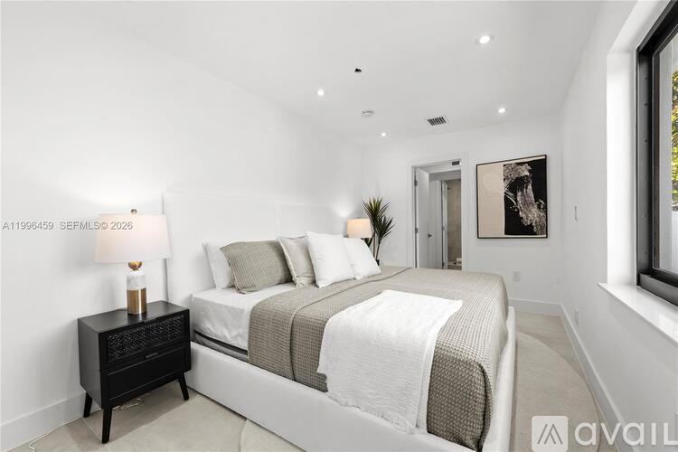 A bedroom with a large bed and a nightstand with a lamp.