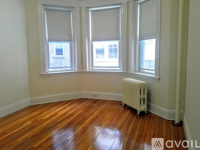 A room with wooden floors and three windows with blinds.