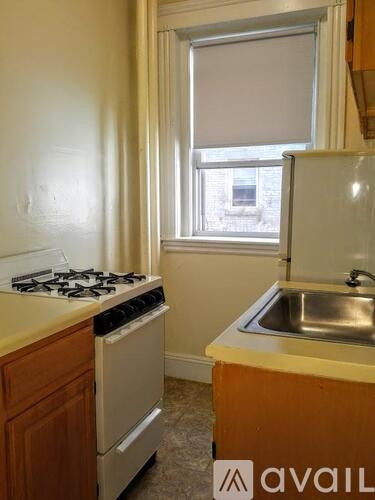 A kitchen with a stove, sink and window.