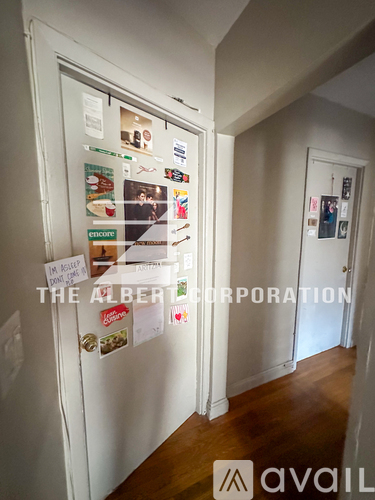 A hallway with a refrigerator covered in magnets and a sign that says "The Albert Corporation".