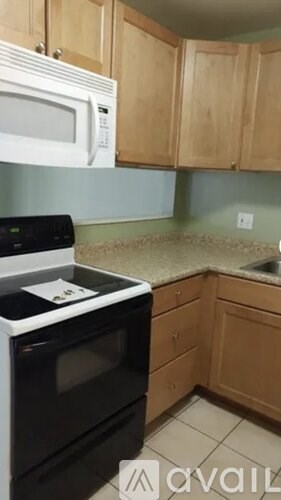 A kitchen with a black stove top oven and a white microwave above it.