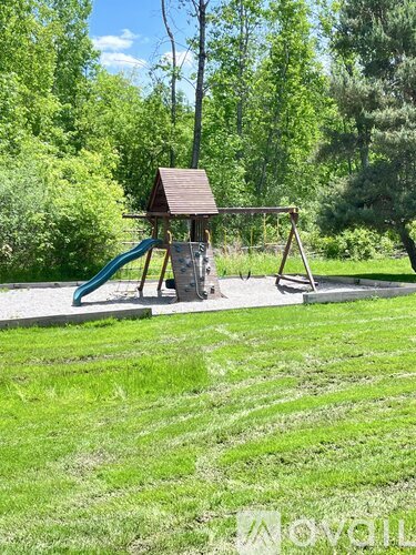 A playground with a green slide and a brown roofed structure.