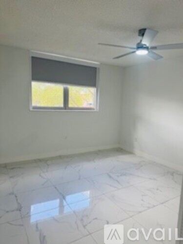 A room with a ceiling fan and a window with blinds.
