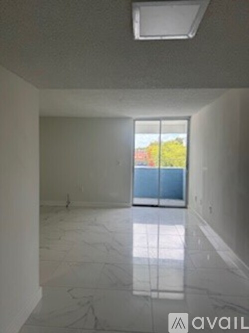 A spacious room with a marble floor and a window overlooking a balcony.