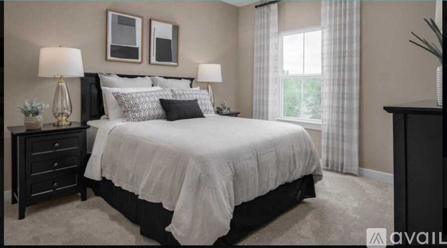 A bedroom with a large bed, two lamps, and a nightstand.