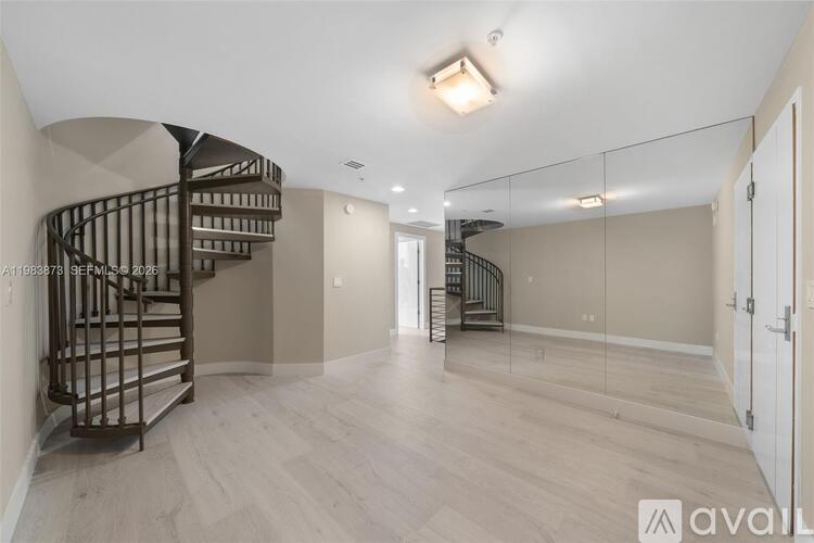 A spacious room with a spiral staircase and wooden flooring.