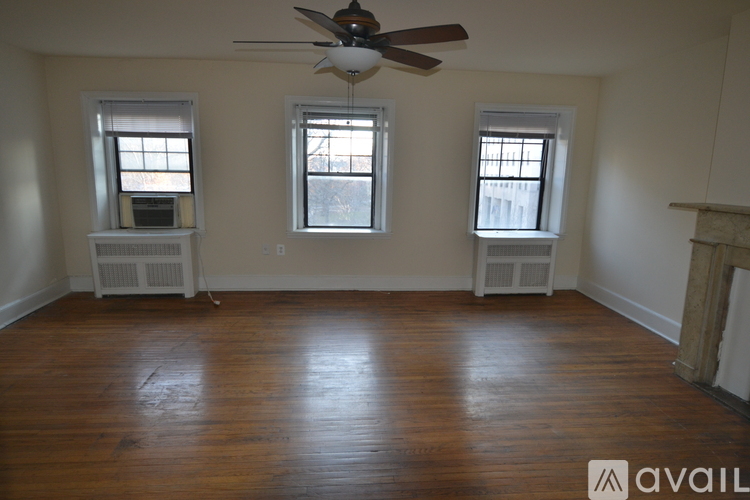 A room with wooden floors and three windows.