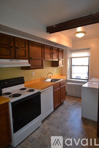 A kitchen with a black stove top oven and wooden cabinets.