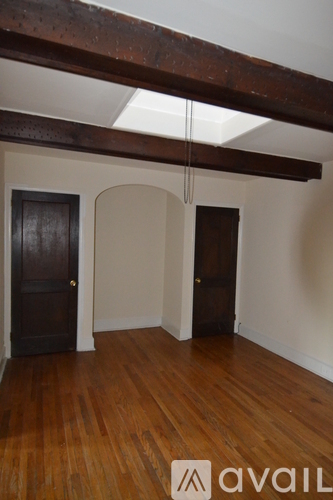A room with wooden floors and a dark brown door.
