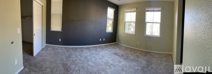 A spacious room with a carpeted floor and a window with blinds.