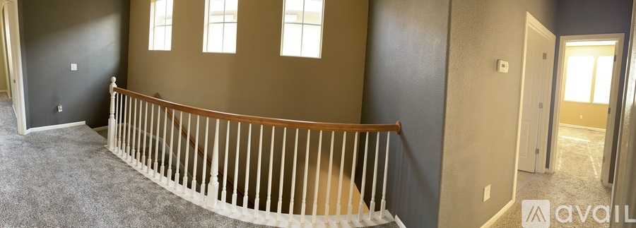 A room with a carpeted floor and a wooden railing.