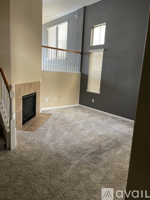 A living room with a fireplace and carpeted floor.