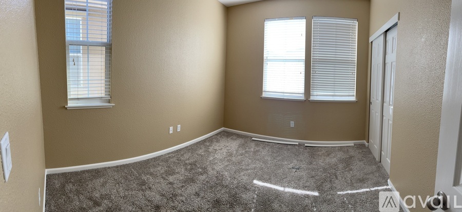A room with a carpeted floor and a window with blinds.