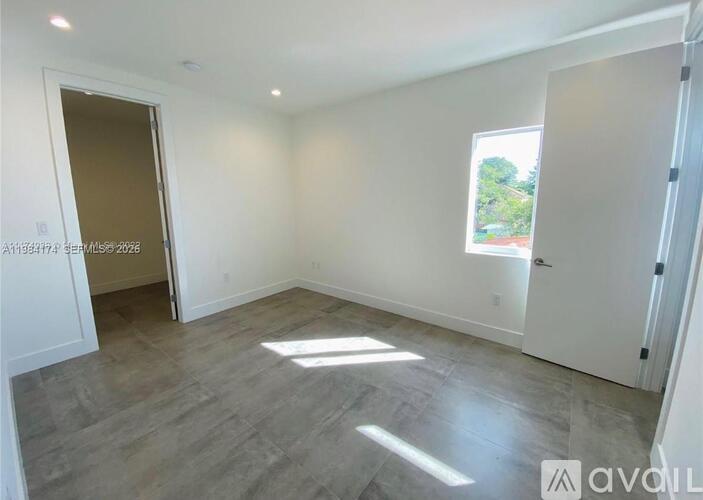 A spacious room with a grey floor and white walls.