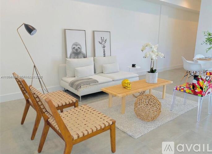 A living room with a white couch, a wooden chair, and a woven basket on the floor.