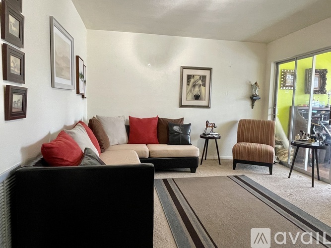 A living room with a black couch and red pillows.
