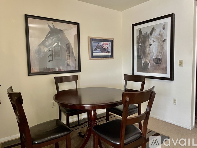 A dining room with a table and chairs and pictures on the wall.
