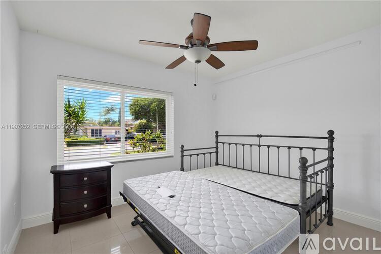 A bedroom with a bed, dresser, and window overlooking a street.