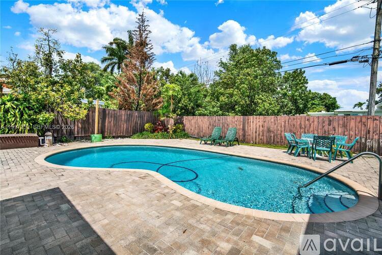 A swimming pool surrounded by a wooden fence and green chairs.