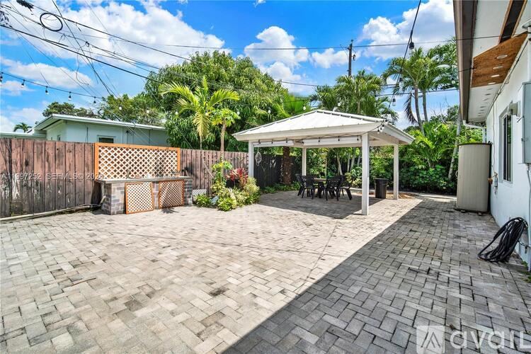 A backyard with a patio, a gazebo, and a fence.