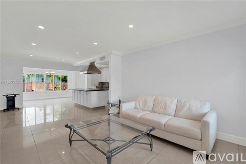 A white couch sits in a spacious living room with a glass coffee table in front of it.